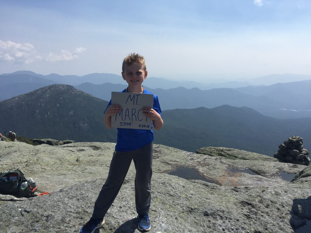 Photo submitted - Sammy Roorda Jr. stands at the top of Mount Marcy holding up a sign with the elevation and date of the accomplishment.