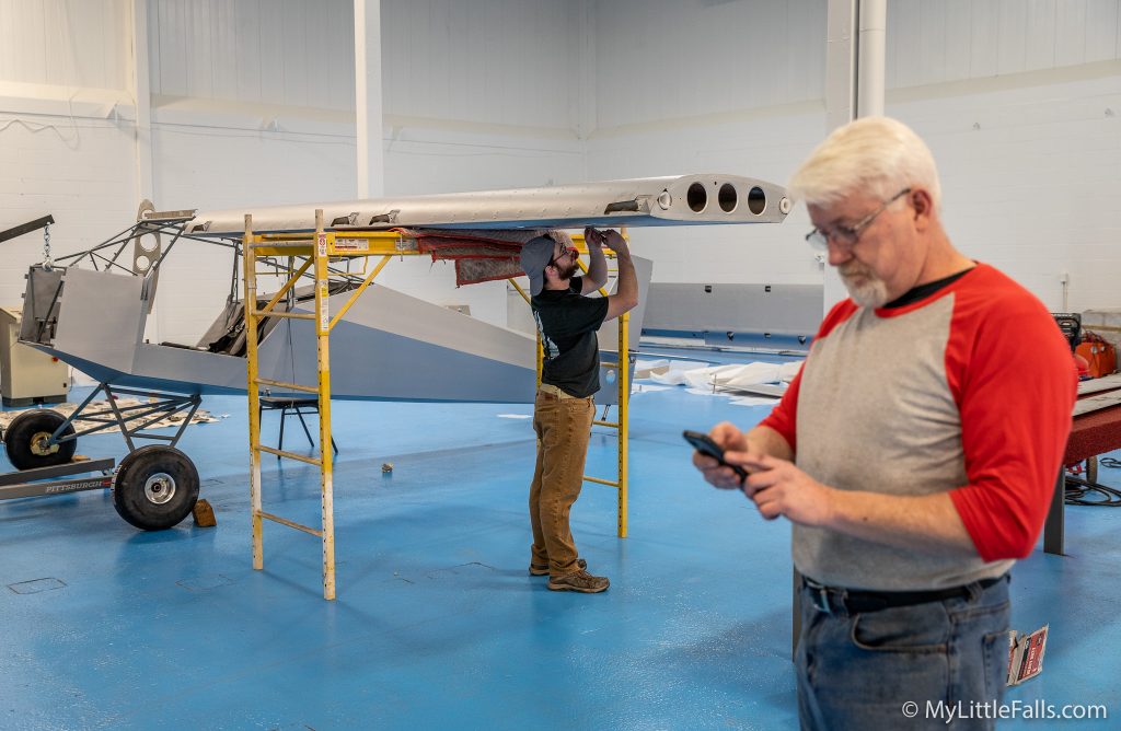 Photo by Dave Warner - William (Willy) Deppmeyer checks the status of a parts order, while Craig Sperry works on the left wing of the SuperStol aircraft that will fly at Oshkosh.