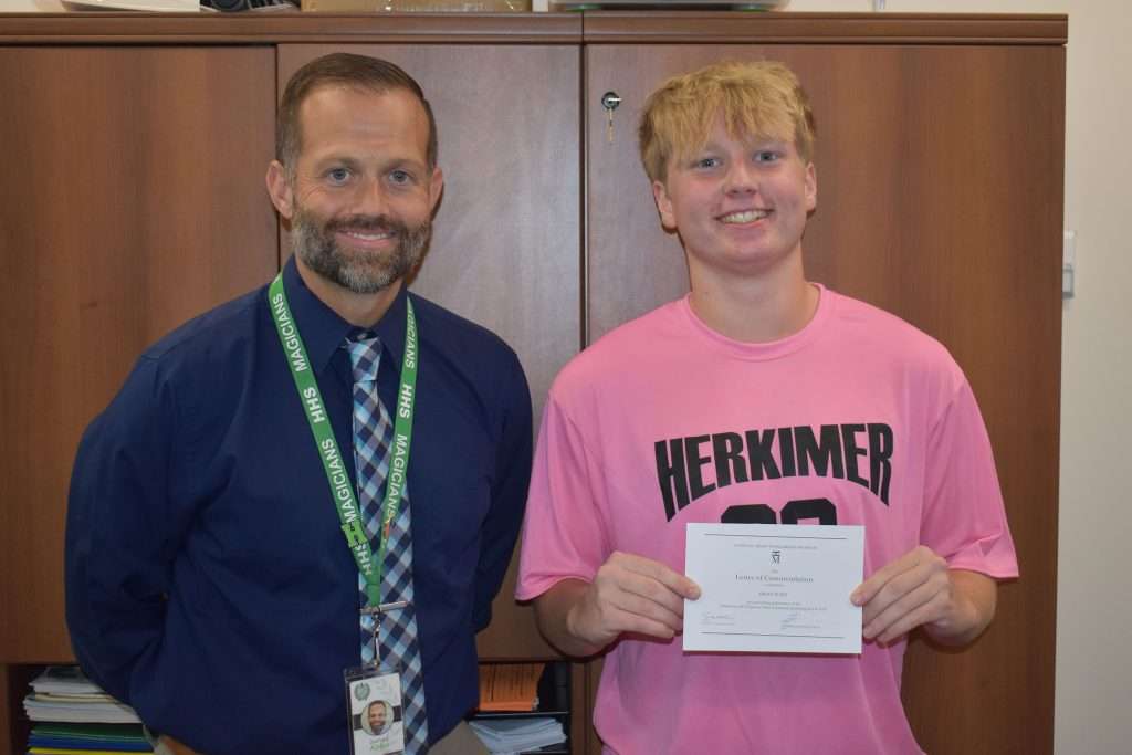 Herkimer Central School District senior Brian Flint (right) holds a Letter of Commendation presented to him by High School Principal Zachary Abbe (left) for earning the status of a Commended Student in the 2025 National Merit Scholarship Program.